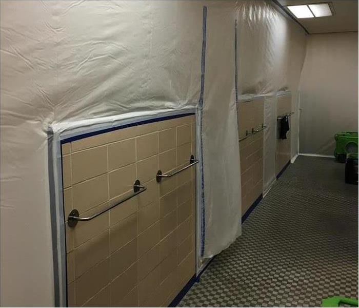 Office bathrooms with water damage covered in tarp for containment from microbial growth