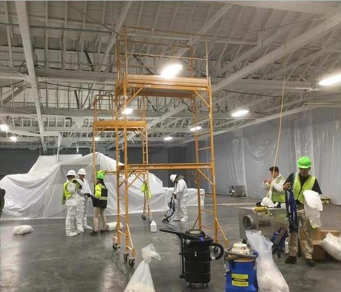 SERVPRO Commercial Team working in a large building with containment and scaffoldings wearing PPE