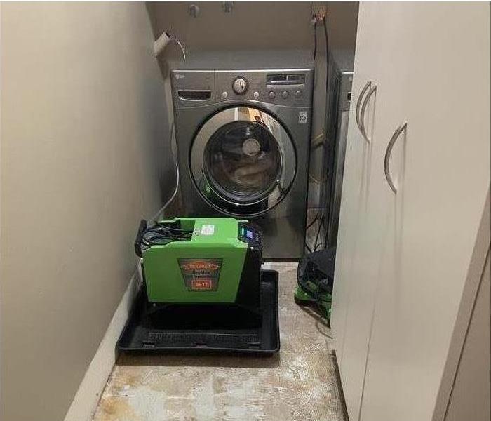 damaged floor with a washer and drying equipment in room